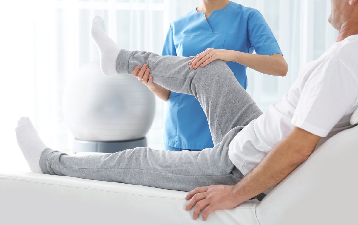 Physiotherapist guiding a patient through a leg stretch