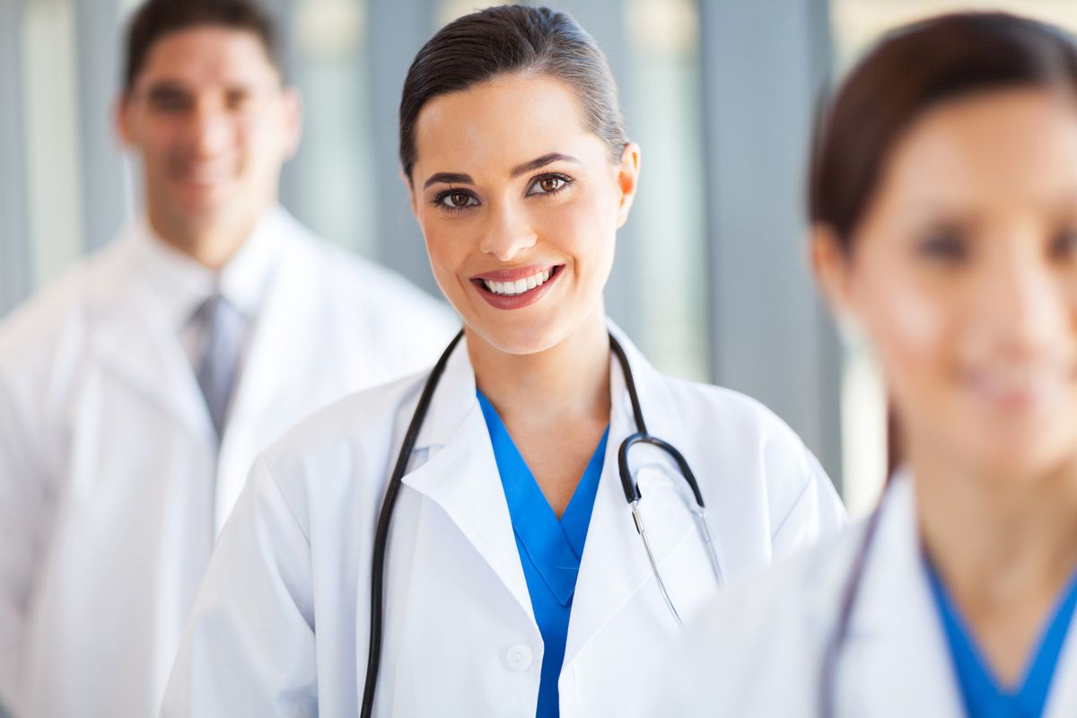 Smiling physician in a white coat standing with two colleagues